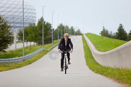 在城市公园骑自行车的商务男性图片