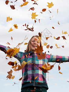 把秋叶抛向空中的女孩图片