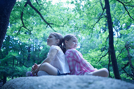 两个女孩坐在森林里的大鹏上图片