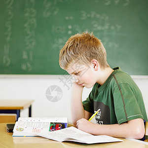 在教室书桌上学习的男孩图片
