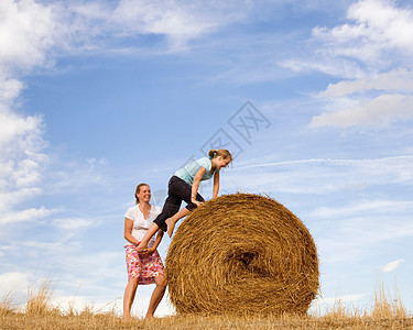 帮女孩爬干草捆的女人图片