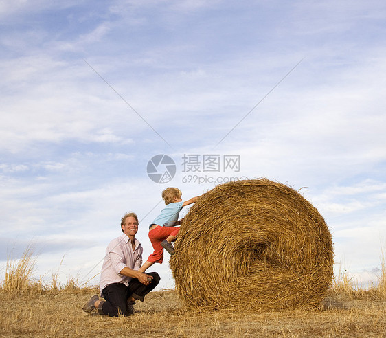 帮男孩爬干草捆的人图片