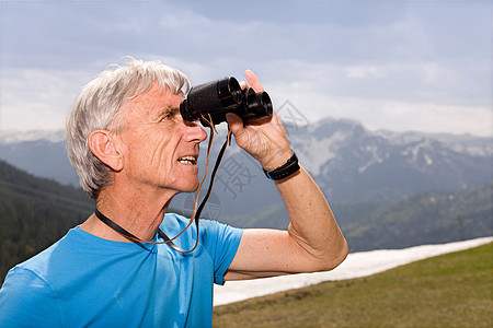 山上带双筒望远镜的老人图片
