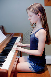 女孩在室内练习钢琴背景图片