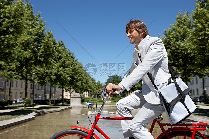 男人带着包骑车穿过城市图片