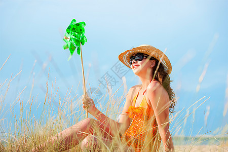 海滩上带风车的女人图片