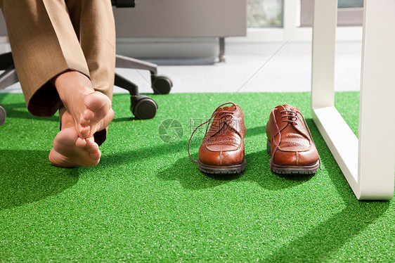 在绿色的办公室地毯上放松的脚图片