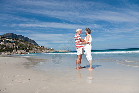 拥抱自然在海滩上拥抱的老年夫妇背景