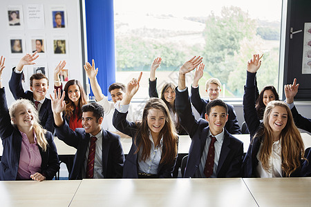 外国人欢呼在教室里举起手的青少年学生背景