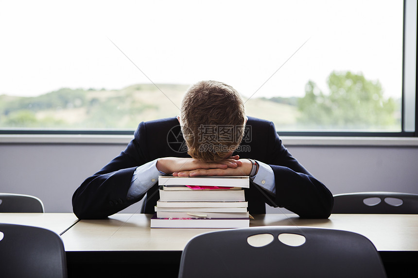 十几岁的男生低着头坐在书桌旁图片