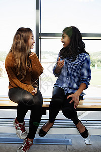 两个十几岁的女学生坐在走廊里聊天图片
