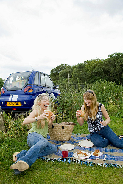 年轻女子在车前吃东西图片