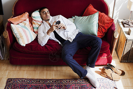 年轻人躺在沙发上看手机图片