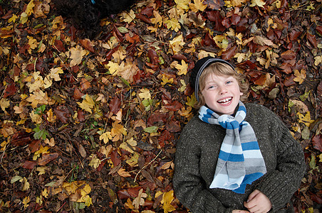 男孩躺在秋叶上图片