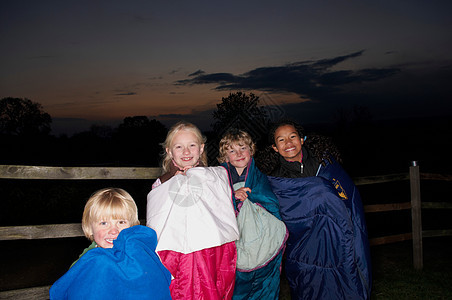 黄昏时孩子们穿着睡袋在外面图片