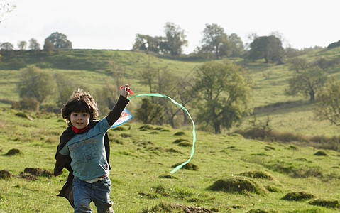 放风筝小男孩小男孩拿着风筝在田里奔跑背景