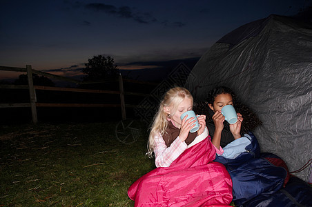 在帐篷附近喝热饮料的女孩图片