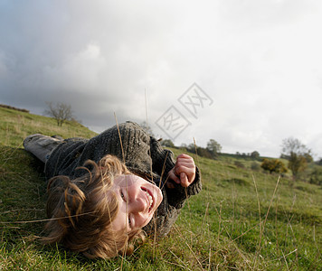 男孩躺在山坡上的草地上图片
