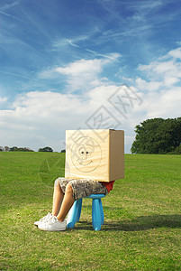 男孩坐在凳子上，盒子放在头上图片