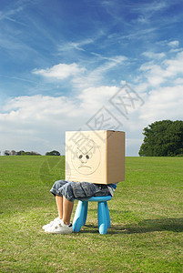 小男孩坐在凳子上，头上戴着盒子图片