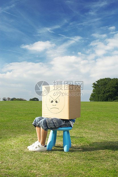 小男孩坐在凳子上，头上戴着盒子图片