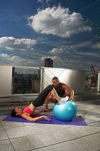 在屋顶上和教练一起锻炼的女人图片