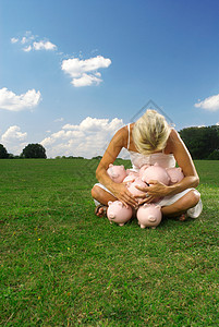 俯视草地拿着小猪存钱罐的女人背景