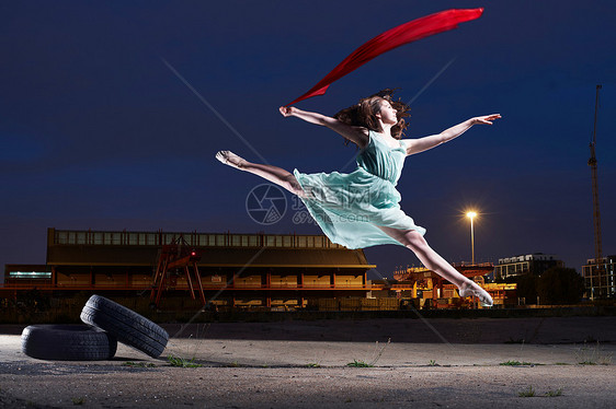 年轻的女舞者在城市环境中跳跃图片