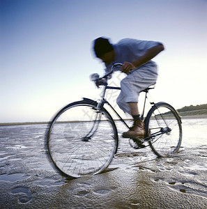 在湿沙滩上骑自行车的人图片