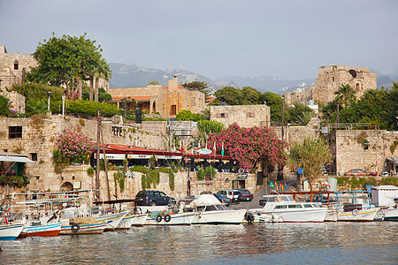 在黎巴嫩的比布罗斯，比布罗斯城堡和餐馆环绕着停泊在码头上的游艇和渔船图片