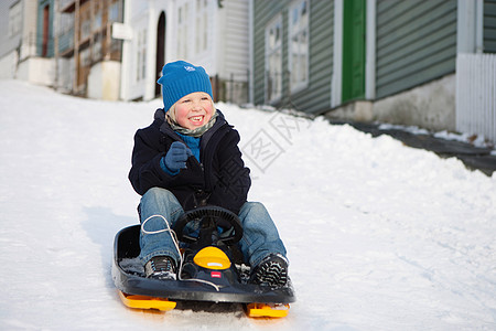 玩雪斯堪的纳维亚男孩在雪橇上背景