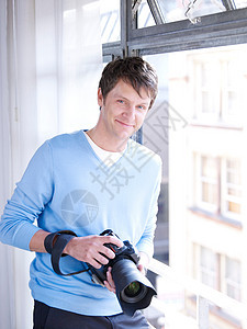 带数码相机的人靠窗拍照图片