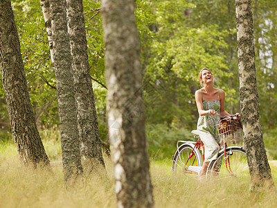 在森林里骑自行车的女人笑着图片