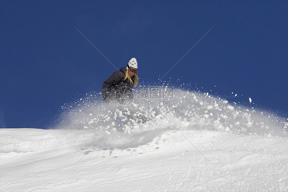在雪中转弯的女滑雪运动员图片
