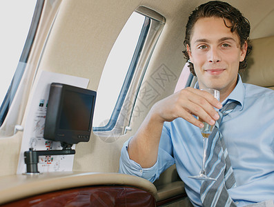 坐在飞机上私人飞机上微笑的商人背景