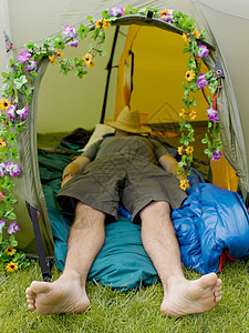 头戴帽子睡在帐篷里的男人图片