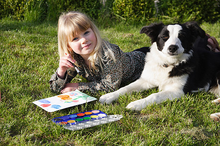 孩子在花园里和她的狗一起画画图片