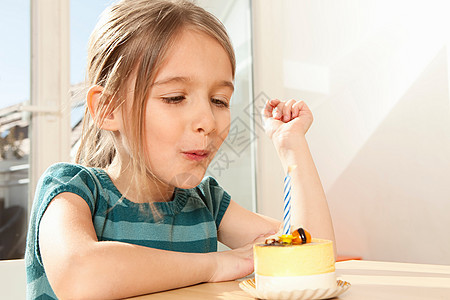 女孩吹灭生日蛋糕上的蜡烛图片