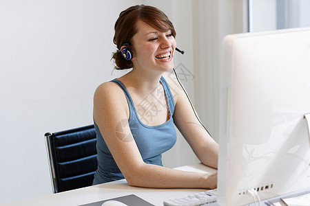 戴着耳机在电脑上工作的女性图片