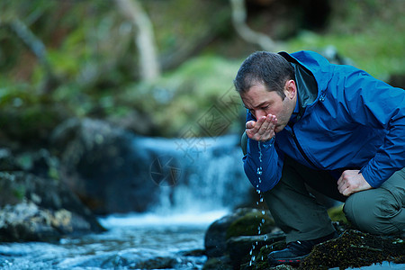 从小溪中饮水的男人图片