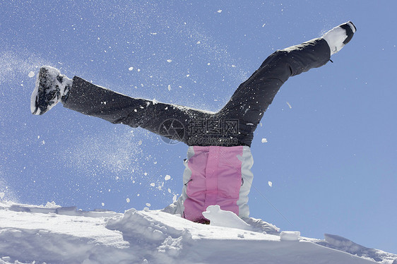 穿滑雪靴的女人在雪地里玩耍图片