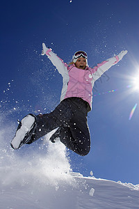 穿滑雪靴的女人在雪地里玩耍图片