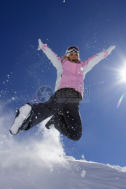 穿滑雪靴的女人在雪地里玩耍图片