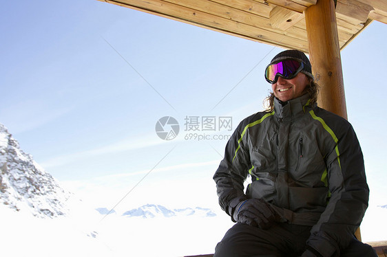 在滑雪小屋阳台上放松的男人图片