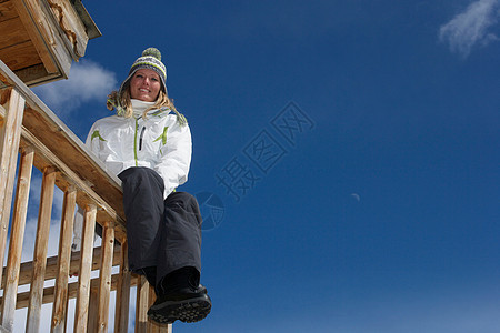 在滑雪小屋阳台上休息的女人图片