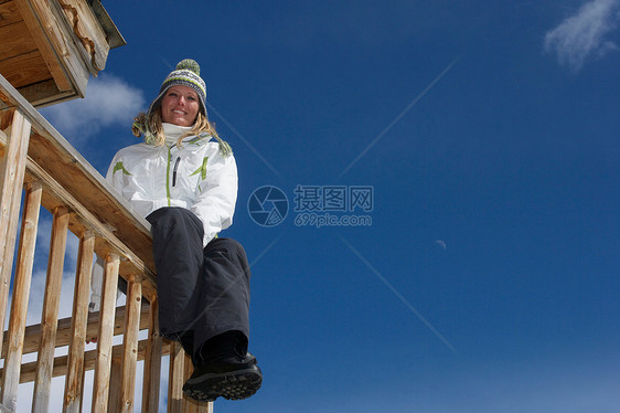 在滑雪小屋阳台上休息的女人图片