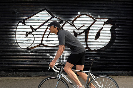 在街上路过涂鸦的男自行车手图片