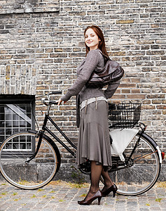 砖墙前骑自行车的女人图片