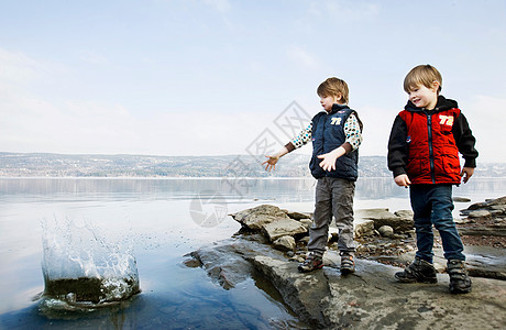 男孩们在湖边玩石头图片