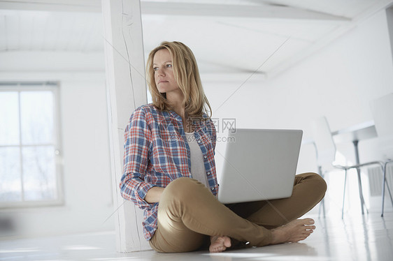 空置办公空间中使用笔记本电脑的成熟女性的肖像图片